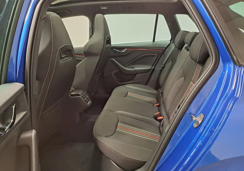 Vue intérieure côté gauche des sièges arrière noirs avec surpiqûres blanches et bandes rouges, portière ouverte du Skoda Kamiq bleu RS.