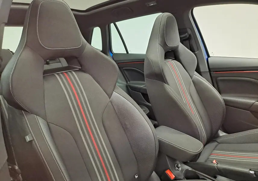 Vue intérieure des sièges avant sport noirs avec surpiqûres blanches et bandes rouges du Skoda Kamiq Monte Carlo bleu RS 2024.
