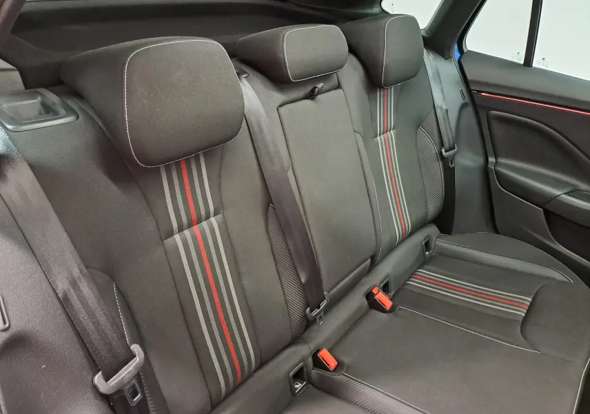 Vue intérieure des sièges arrière du Skoda Kamiq Monte Carlo 2024, tissu noir avec bandes grises et rouges, ceinture de sécurité visible.