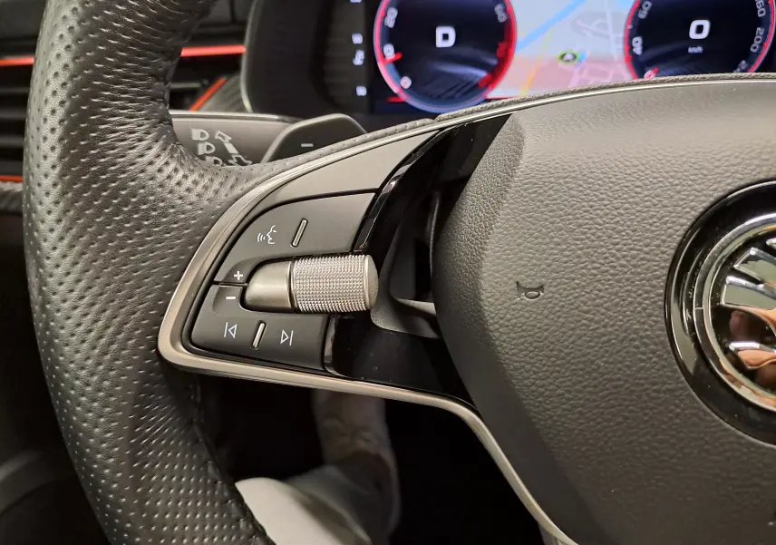Gros plan sur le volant noir perforé côté gauche du Skoda Kamiq 2024 avec commandes intégrées et tableau de bord digital.