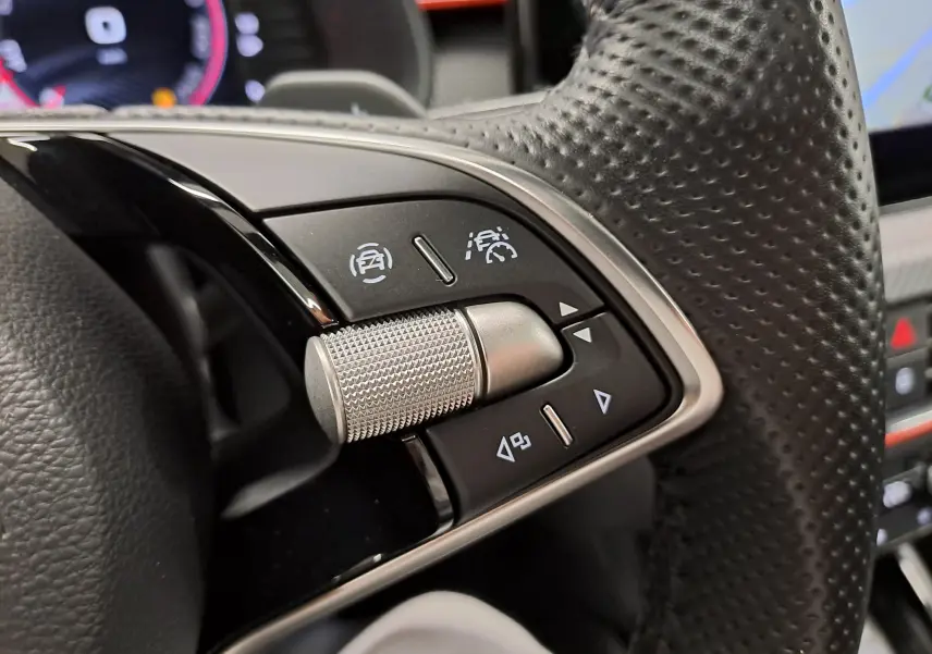 Gros plan sur les commandes au volant à droite du Skoda Kamiq 2024, avec molette métallique et boutons noirs.