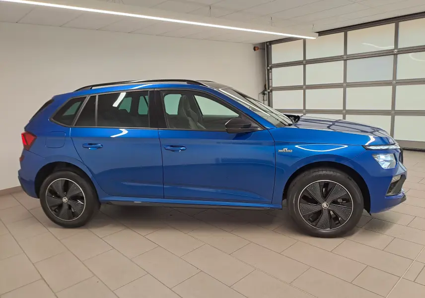 Vue de profil côté gauche du Skoda Kamiq 1.5 TSI 150 DSG7 Monte Carlo en bleu RS avec jantes noires distinctives.