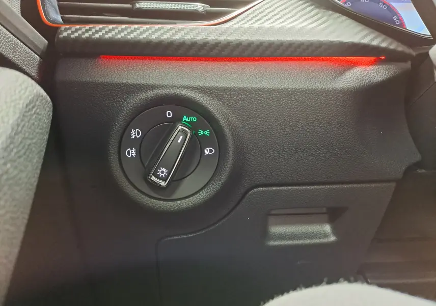 Gros plan sur le bouton de réglage des phares avec éclairage LED rouge intérieur du Skoda Kamiq Bleu RS 2024.