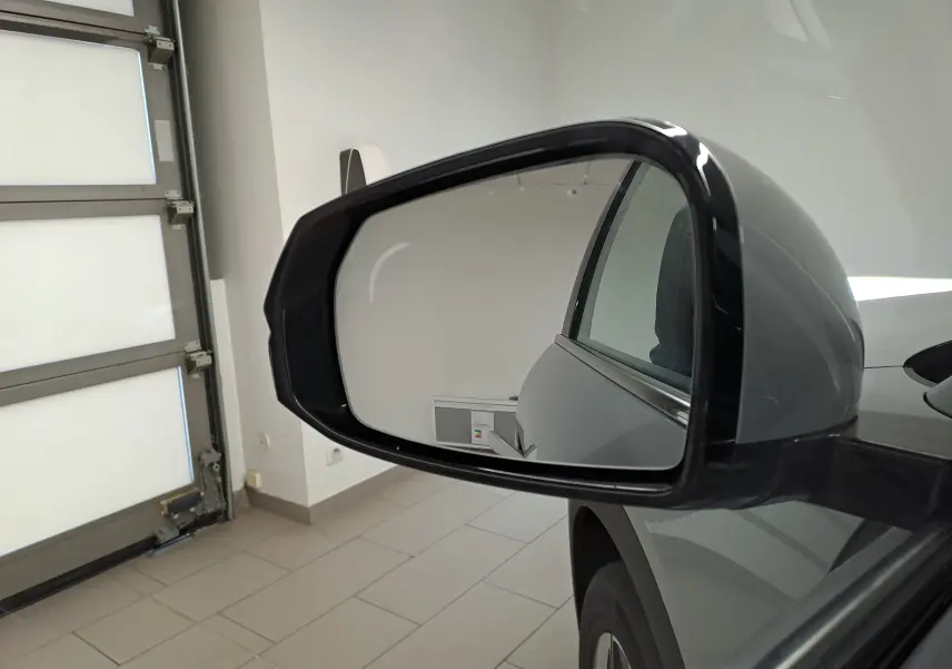 Rétroviseur côté droit du Geely E5 PRO gris Moonlight 2026, vue rapprochée en intérieur avec reflet du mur blanc.