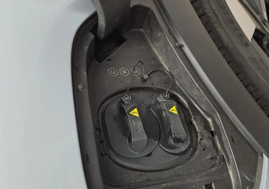 Prise de recharge électrique ouverte côté gauche du Geely E5 PRO gris Moonlight, avec détail des bouchons de connexion.
