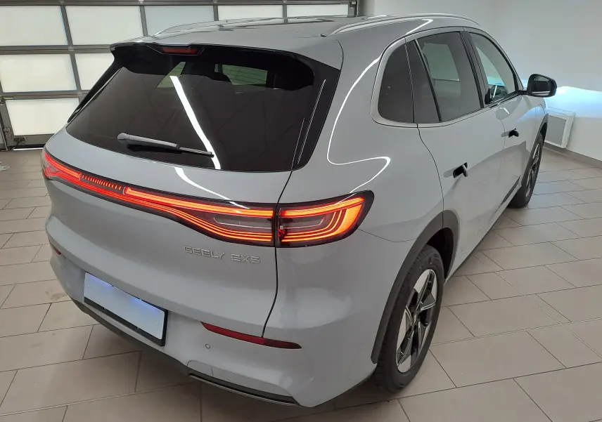 Vue 3/4 arrière droite du SUV électrique Geely E5 PRO gris Moonlight avec feux arrière allumés en intérieur.