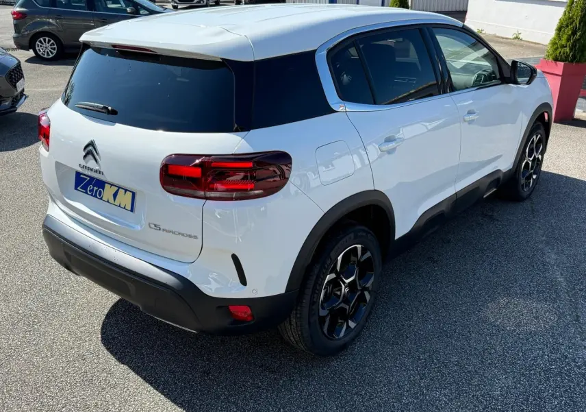 Vue 3/4 arrière droite du Citroën C5 Aircross blanc banquise avec toit noir et jantes bi-ton distinctives.