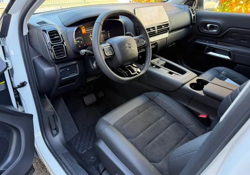 Intérieur côté conducteur du Citroën C5 Aircross blanc banquise 2024, avec tableau de bord numérique et sièges en cuir noir.