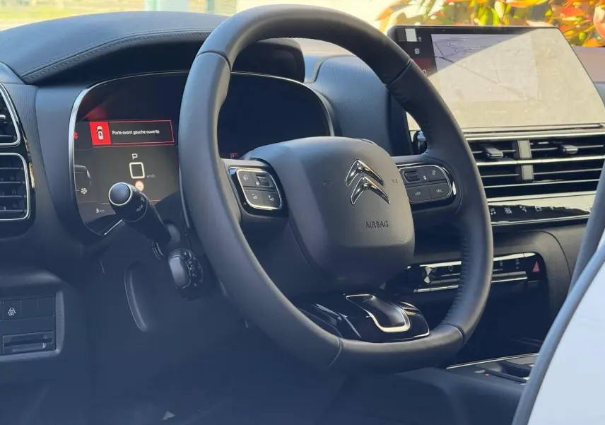 Intérieur du Citroën C5 Aircross 2024, vue du volant cuir noir et tableau de bord numérique avec écran tactile.