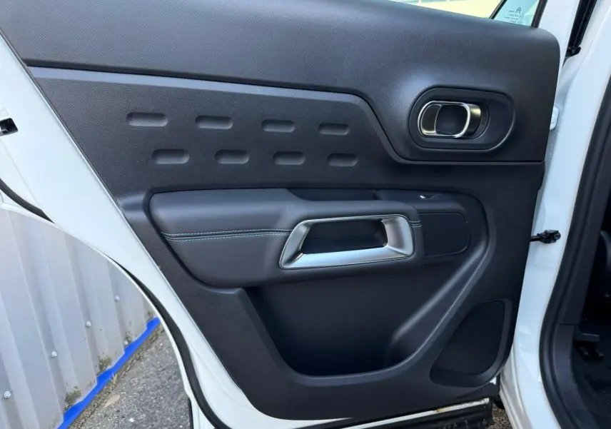 Vue rapprochée de la porte arrière gauche blanche banquise du Citroën C5 Aircross 2024 avec poignée intérieure design.