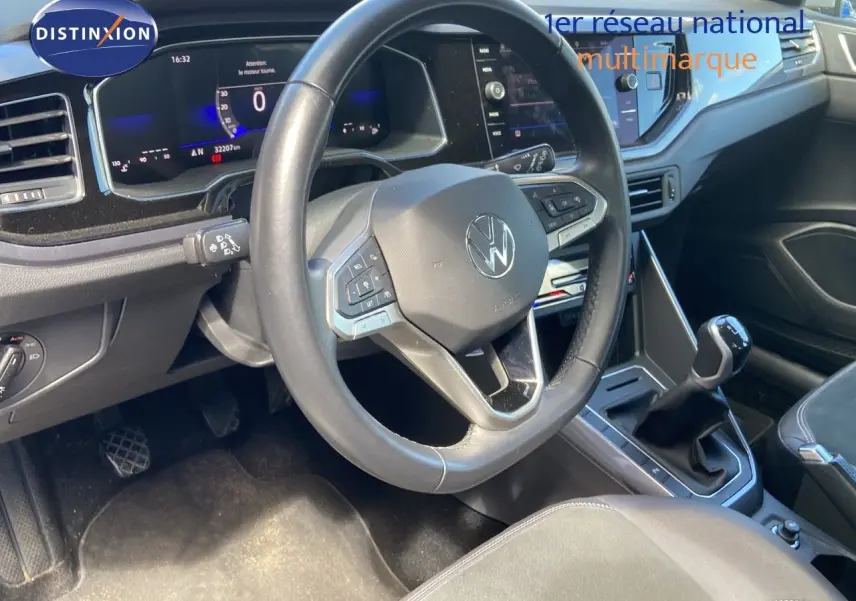 Intérieur de Volkswagen Polo 1.0 TSI 2023 montrant le volant, tableau de bord numérique et levier de vitesse manuel.