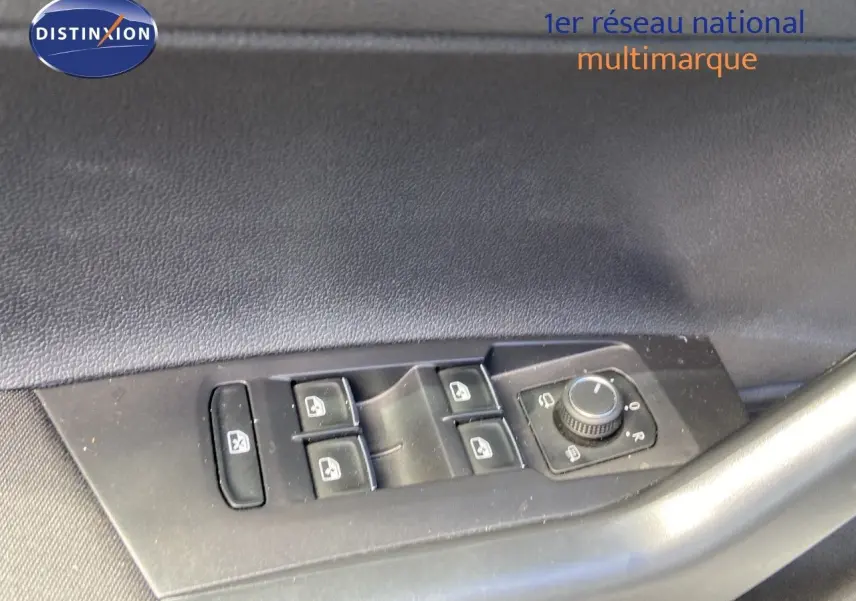 Gros plan sur les commandes de lève-vitres et réglage des rétroviseurs côté conducteur d'une Volkswagen Polo argentée.