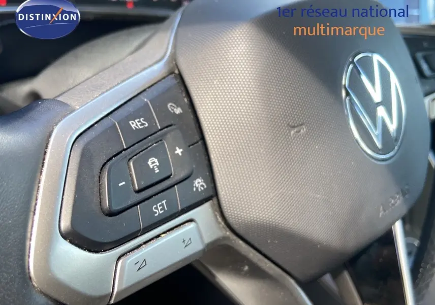 Gros plan sur le volant de la Volkswagen Polo 2023 avec commandes intégrées et logo VW argenté au centre.