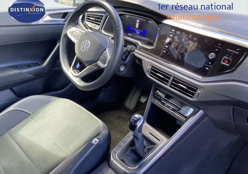 Intérieur avant gauche de Volkswagen Polo 2023 argent, volant multifonctions, boîte manuelle et tableau de bord digital.