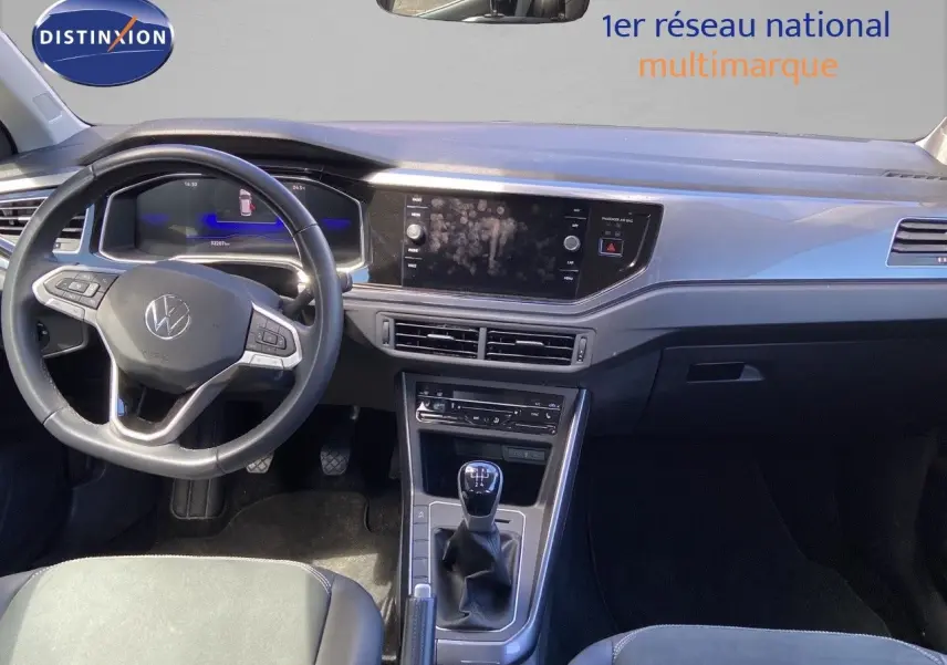 Vue intérieure de face du tableau de bord et levier de vitesse manuel d'une Volkswagen Polo 2023 finition Style en reflet d'argent métal.