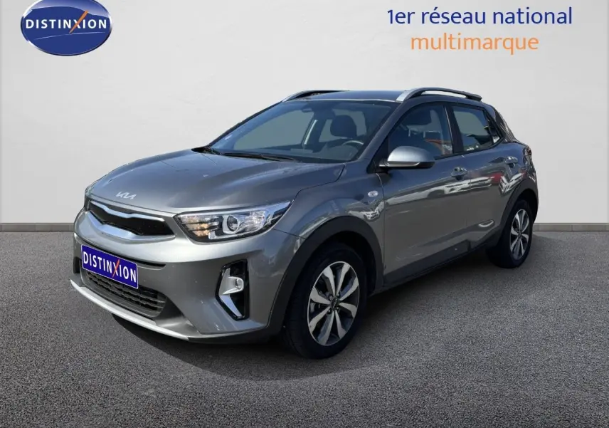 KIA STONIC gris météore en 3/4 avant droit, avec jantes bi-ton et toit ouvrant visible sur fond neutre.