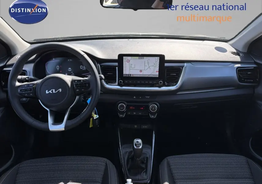 Vue intérieure avant du Kia Stonic 2024 essence gris météore, tableau de bord avec écran tactile et boîte manuelle.