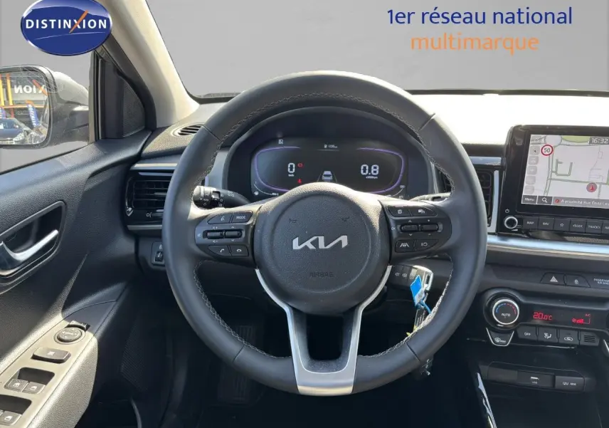 Vue intérieure centrée sur le volant du Kia Stonic gris météore 2024 avec tableau de bord numérique et écran GPS.
