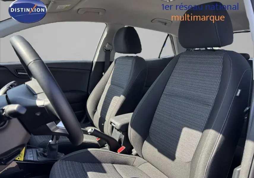 Intérieur du Kia Stonic 2024 montrant les sièges avant en tissu gris et le volant côté gauche.