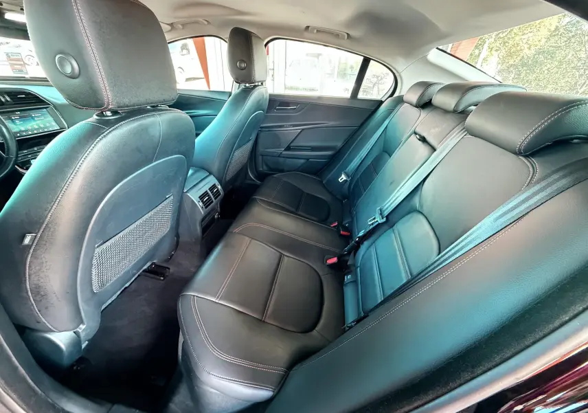 Vue intérieure arrière côté droit montrant les sièges en cuir noir et les appuie-têtes de la Jaguar XE 2019.