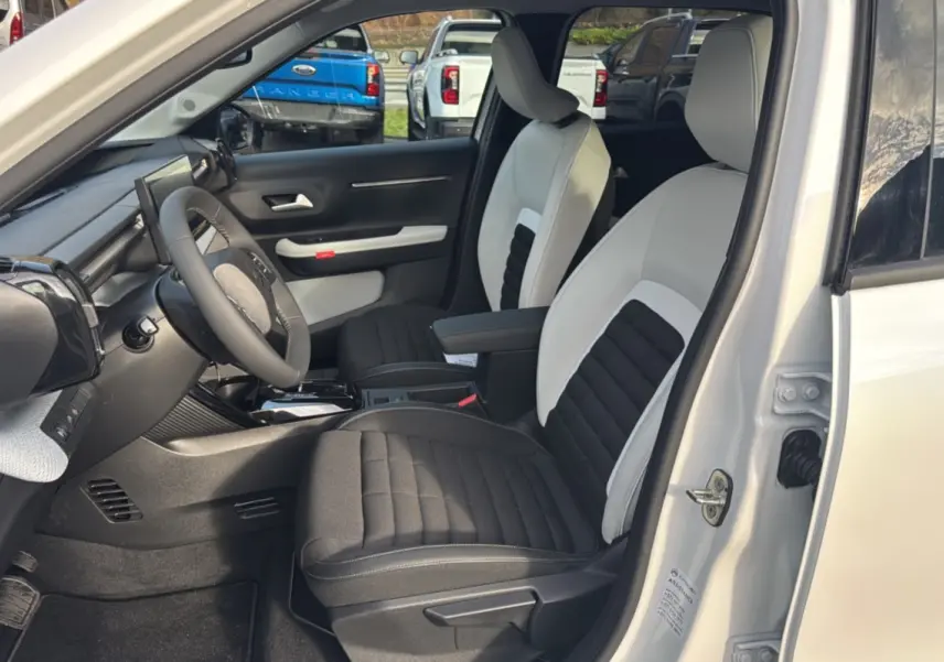 Vue intérieure côté conducteur du Citroën C3 Aircross blanc banquise, sièges tissu bicolores avec accoudoir central.