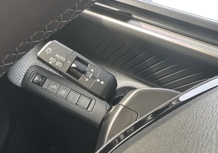 Gros plan sur la commande des feux et clignotants côté gauche du volant d'une Citroën C3 Aircross blanc banquise.