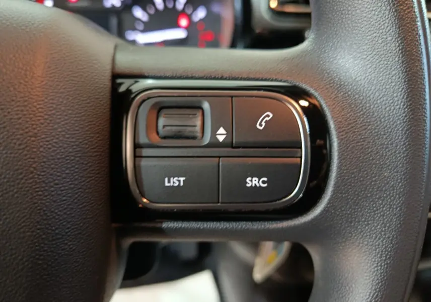 Gros plan sur les commandes gauche du volant noir de la Citroën C3 PureTech 83 BVM MAX 2024, avec boutons multifonctions.