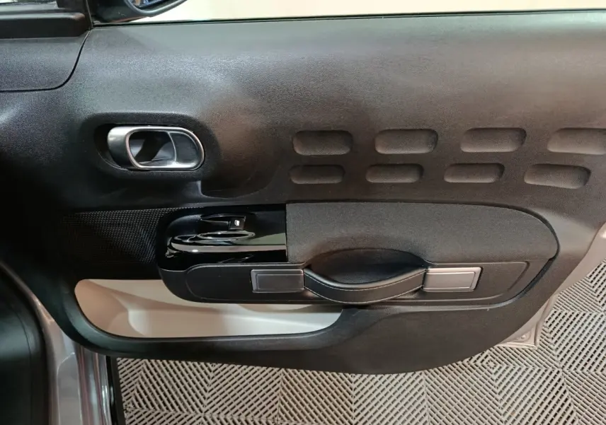 Vue rapprochée de la porte côté conducteur gris foncé de la Citroën C3 avec poignée intérieure noire et détails texturés.