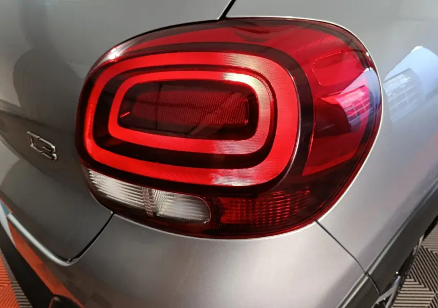 Gros plan sur le feu arrière droit rouge et blanc d'une Citroën C3 gris foncé 2024, avec logo C3 visible.