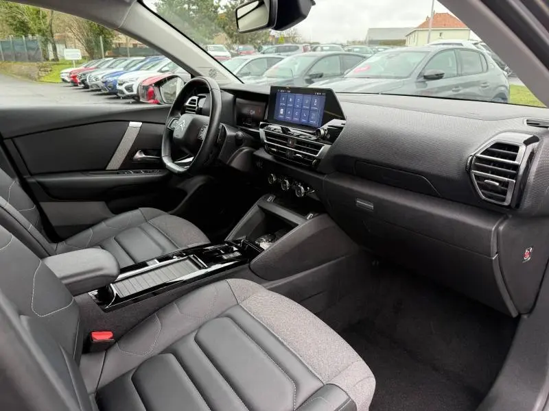 Vue intérieure côté conducteur du Citroën C4 X 2024 gris, avec tableau de bord moderne et écran tactile central.
