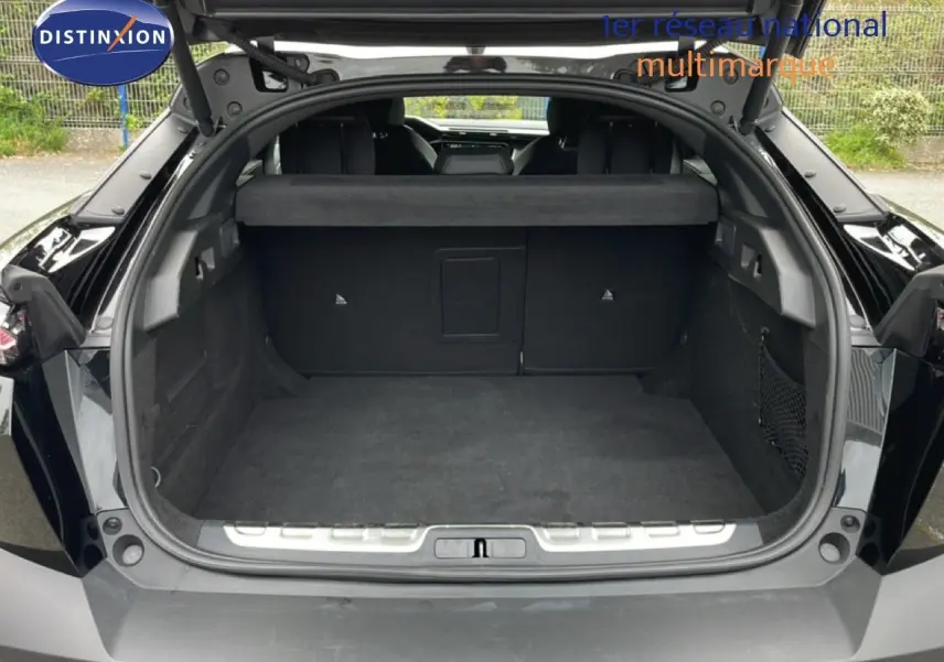 Coffre ouvert vu de l'arrière d'une Peugeot 408 HYBRID 145CH GT noir métal, montrant un espace de chargement spacieux.