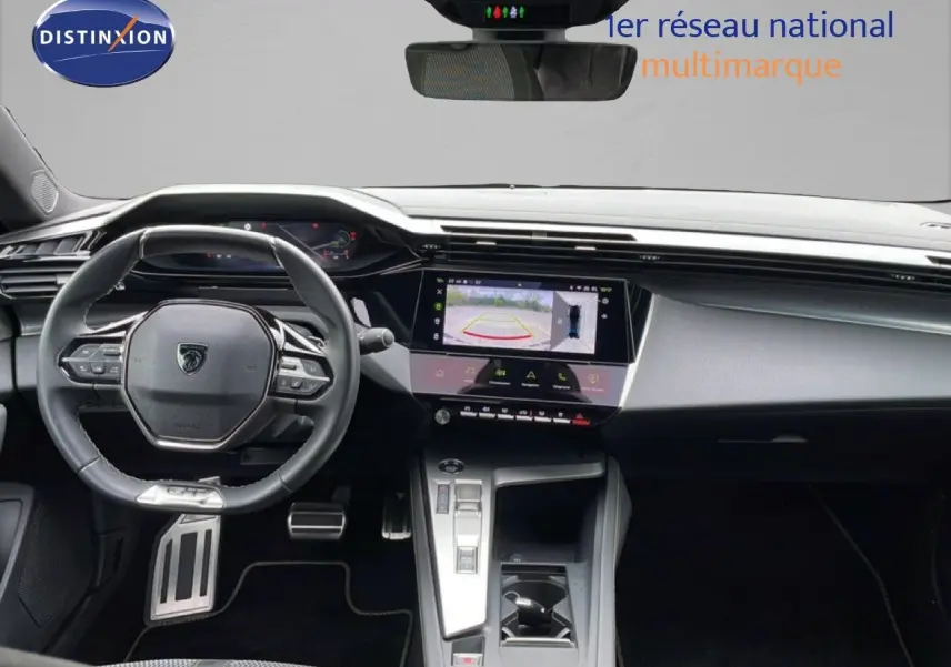 Vue intérieure frontale du tableau de bord et volant noir de la Peugeot 408 Hybrid 145ch avec écran tactile et caméra de recul affichée.