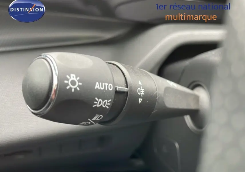 Gros plan sur la commande d’éclairage côté gauche du volant d’une Peugeot 408 Hybrid 2024 noir métal.