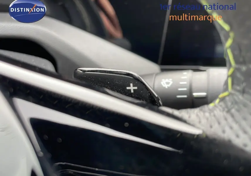 Gros plan sur la palette de changement de vitesse + du volant cuir noir avec surpiqûres jaunes dans une Peugeot 408 Hybrid 2024.