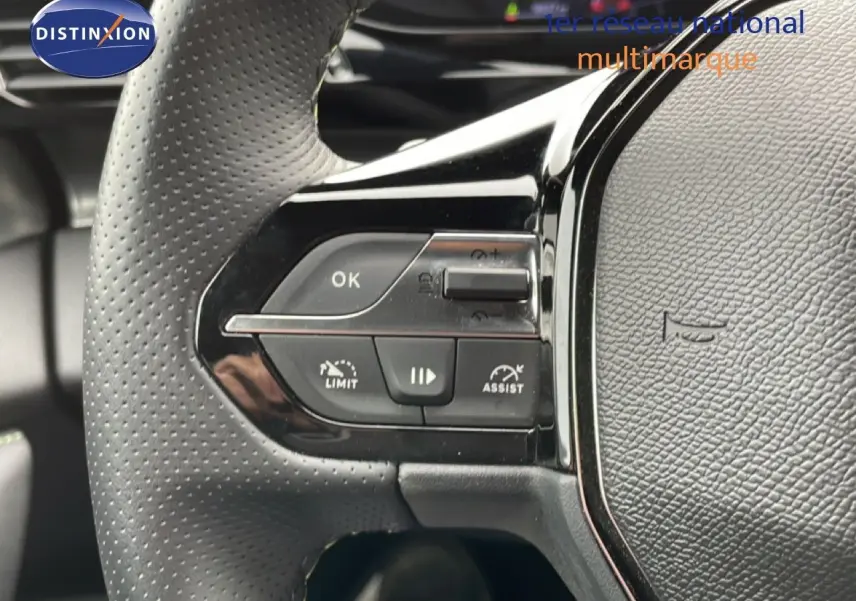 Gros plan sur les commandes gauche du volant cuir perforé noir du Peugeot 408 Hybrid 2024.