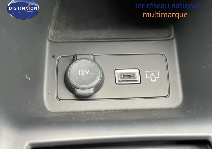 Gros plan sur la prise 12V et port USB-C du Peugeot 408 Hybrid 145ch GT noir métal, intérieur visible en arrière-plan.