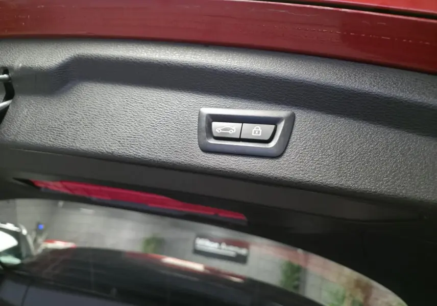 Bouton de fermeture électrique du hayon sur la partie intérieure du coffre d'une BMW X2 orange.