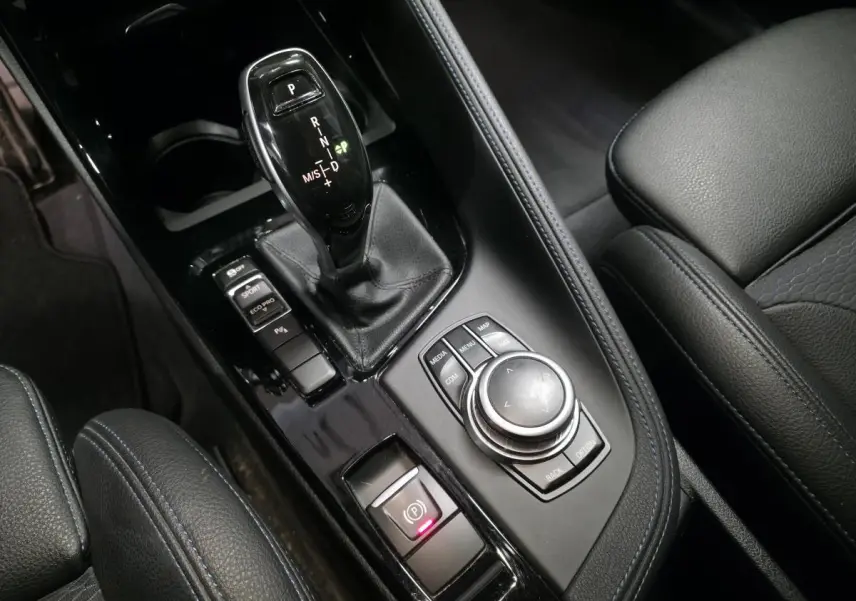 Gros plan sur la console centrale noire avec levier de vitesse automatique et commandes du BMW X2 sDrive 18d M Sport.