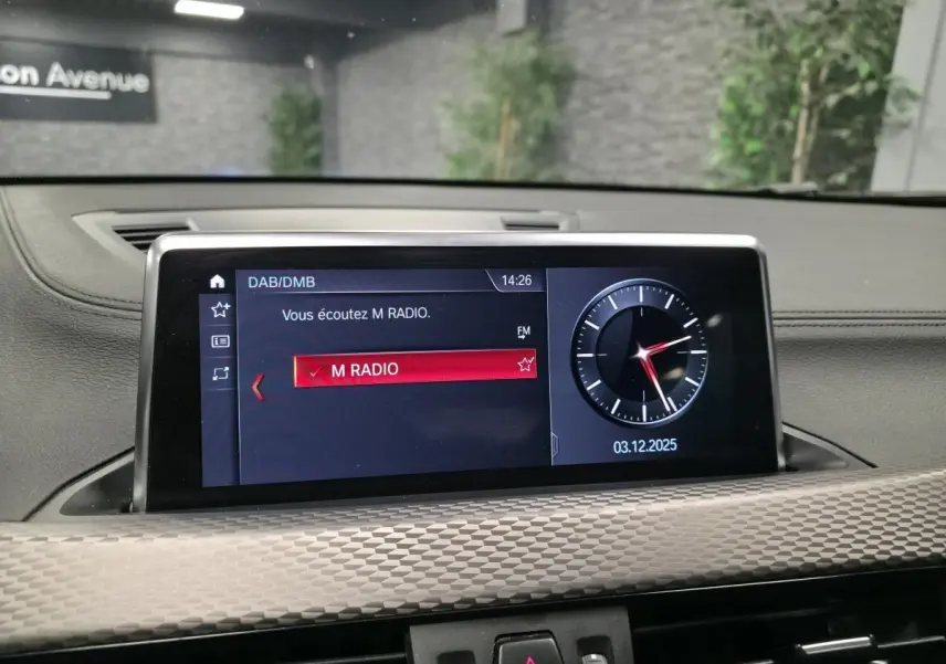 Écran multimédia intérieur BMW X2 M Sport 2021 affichant la radio M RADIO et une horloge digitale.
