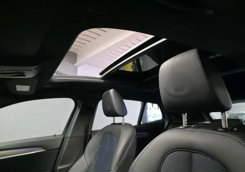 Vue intérieure sur les sièges avant en cuir noir et toit ouvrant panoramique du BMW X2 orange F39 M Sport 2021.