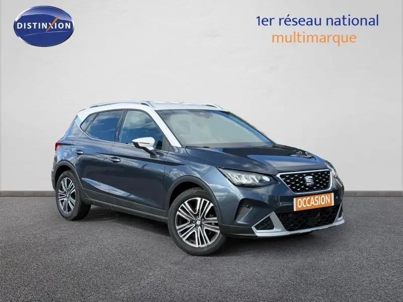 SEAT Arona 2025 bleu saphir métal avec toit blanc vu en 3/4 avant, mettant en valeur ses jantes et calandre distinctive.
