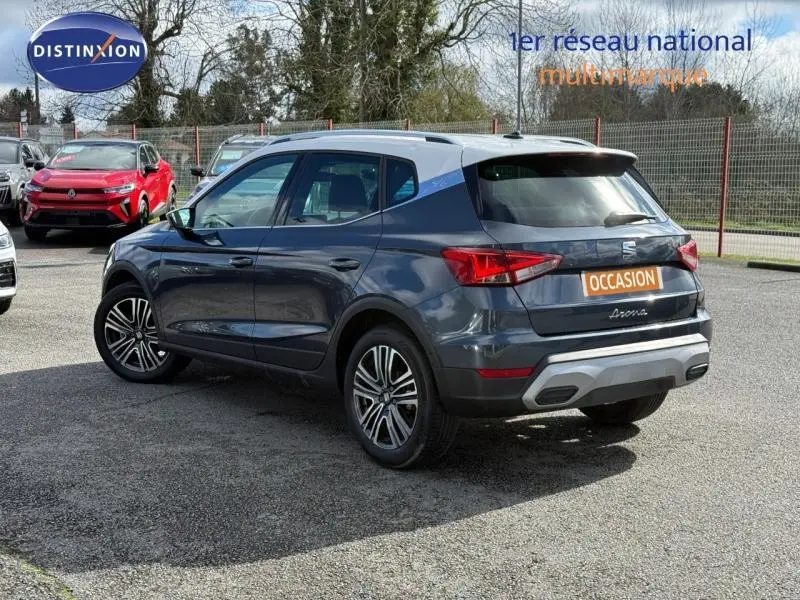 Vue 3/4 arrière droite du SEAT Arona 2025 bleu saphir métal avec toit blanc, soulignant son design compact et ses jantes alliage.