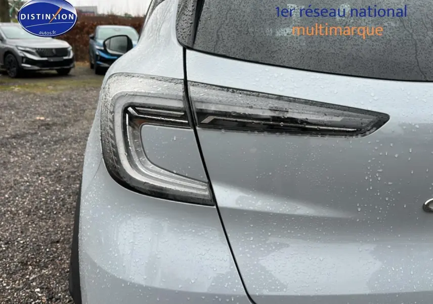 Gros plan sur le feu arrière gauche du Renault Captur gris rafale 2025 sous la pluie, avec gouttes visibles.
