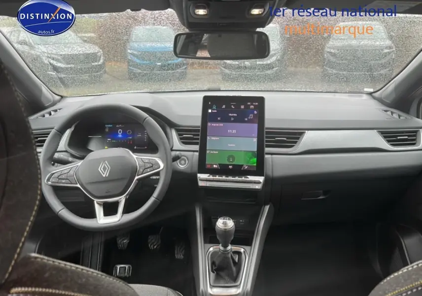 Vue intérieure avant du tableau de bord gris du Renault Captur 2025 avec écran tactile vertical et volant multifonction.