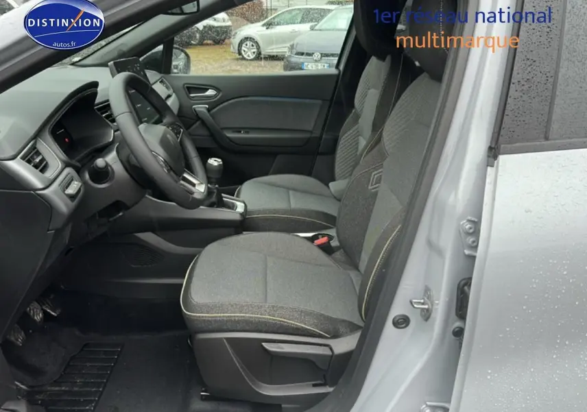 Vue intérieure côté conducteur du Renault Captur gris rafale 2025, avec sièges tissu gris et volant multifonction.