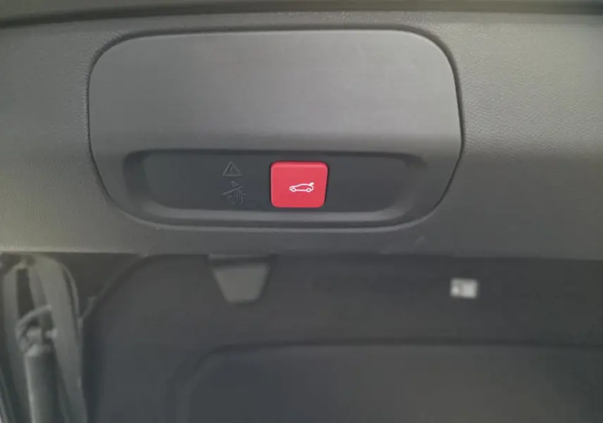 Bouton rouge d'ouverture électrique du hayon sur la partie intérieure du coffre d'une Peugeot 408 gris Selenium.