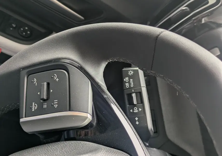 Gros plan sur le volant et commandes du tableau de bord intérieur du Citroën C3 Aircross gris mercuy avec toit noir.