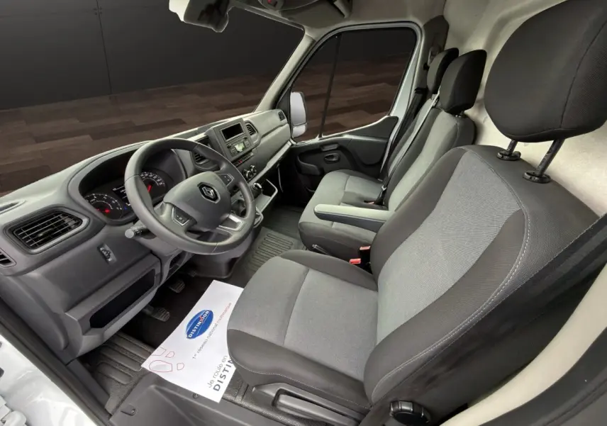 Vue intérieure côté conducteur du Renault Master blanc 2024, montrant le tableau de bord et les sièges gris.