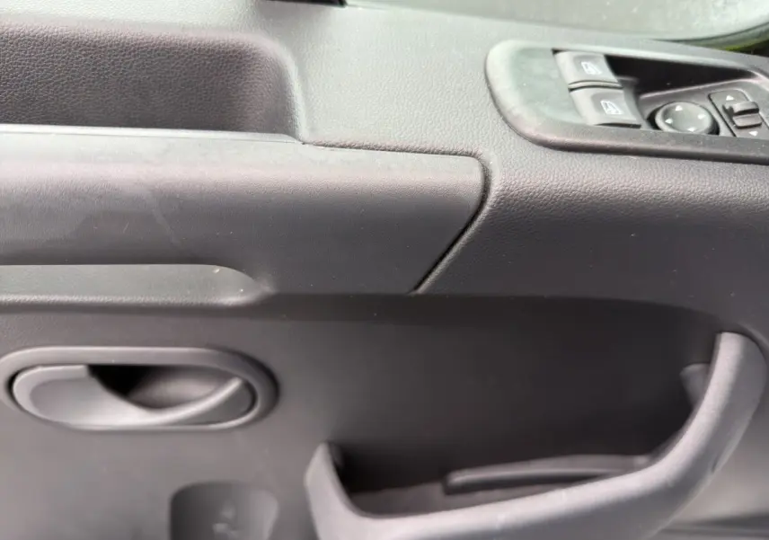 Gros plan sur la porte intérieure côté conducteur du Renault Master 2024, avec commandes de vitres électriques et poignée noire.