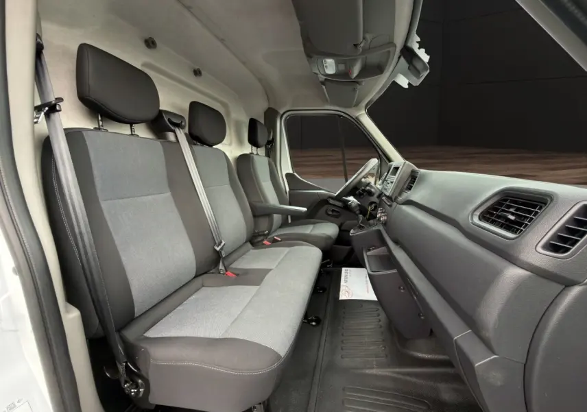 Vue intérieure côté passager du Renault Master blanc 2024, montrant les sièges gris et la planche de bord noire.